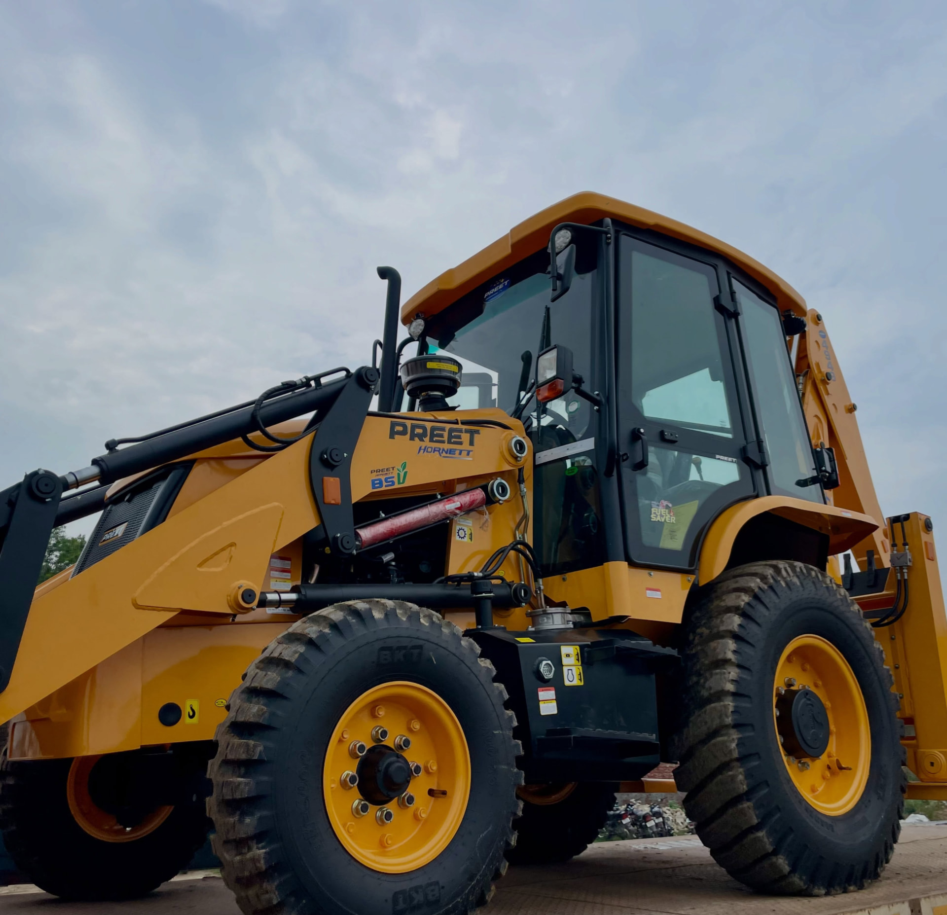 Yellow Preet backhoe loader digging at a construction site in Maharashtra